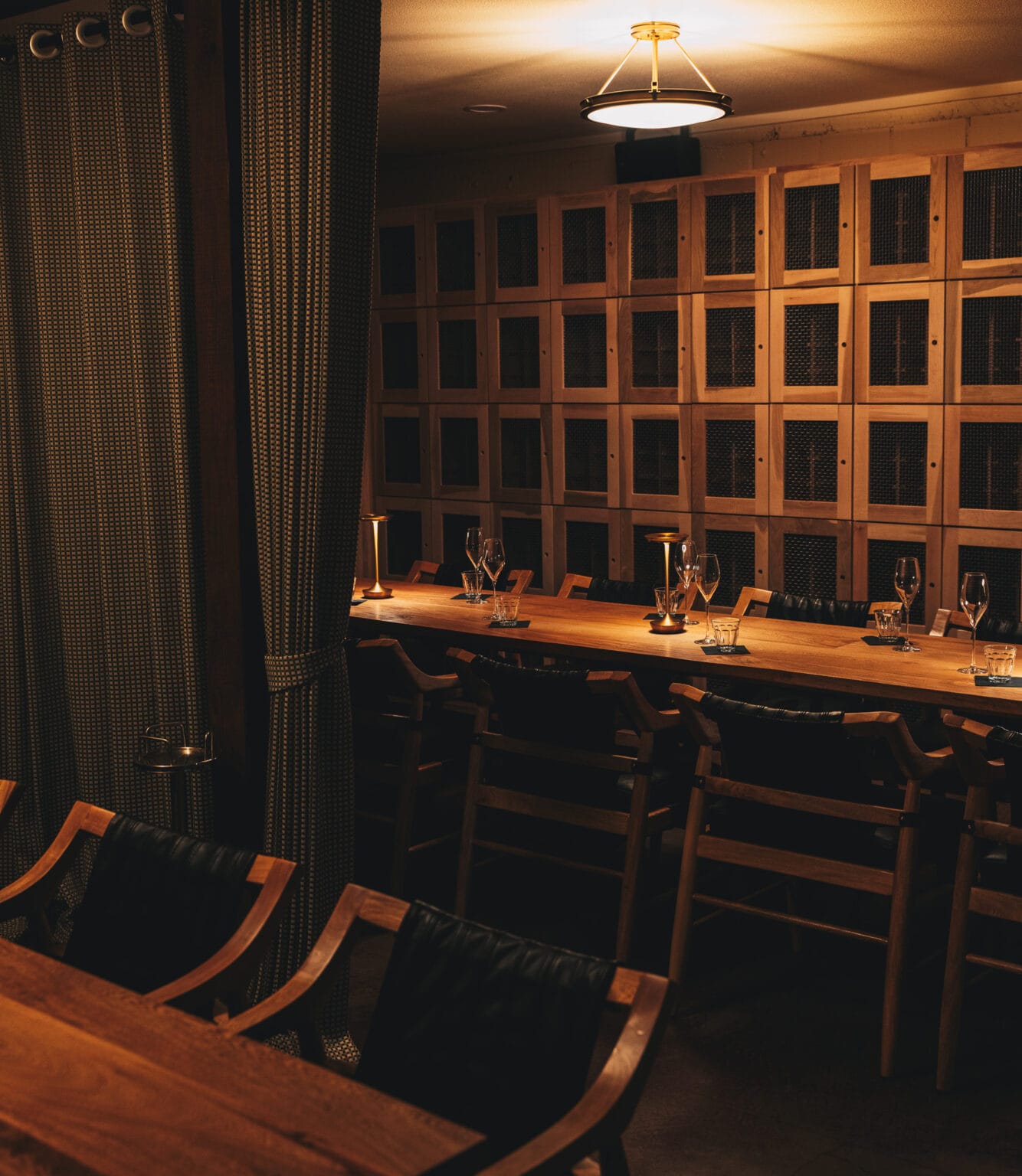 The long communal table in the member’s lounge, set with glasses and lamplight