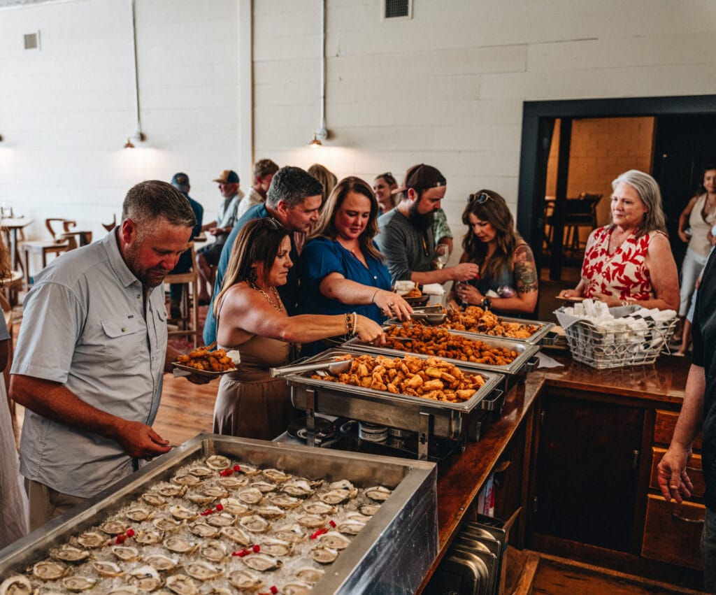 Guests gathered around a long table set with food during an event at Rebecca Caroline