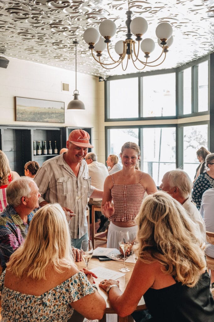 Guests standing and talking in the tasting room by the front windows