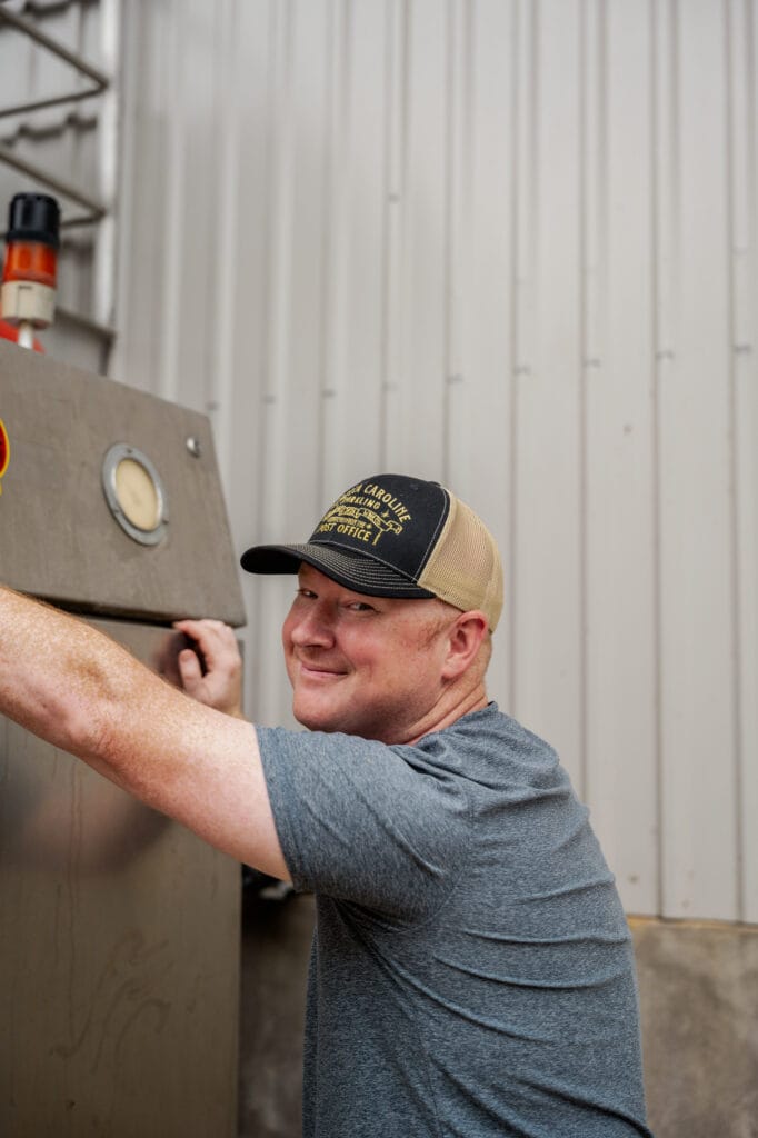 A cellar hand opening a tank hatch outside the winery