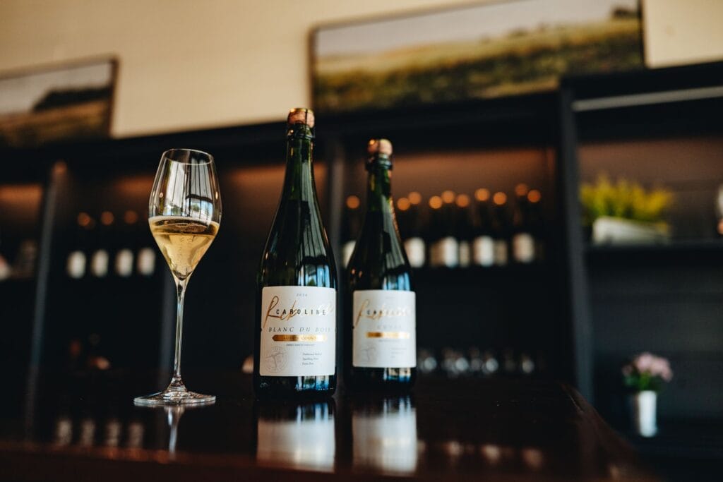 Rebecca Caroline October release wines with a poured glass at the bar